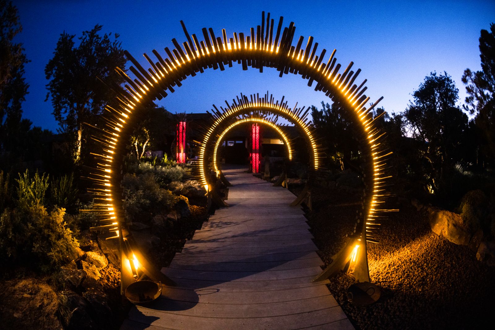 Illuminated sculptural archways leading through an outdoor event